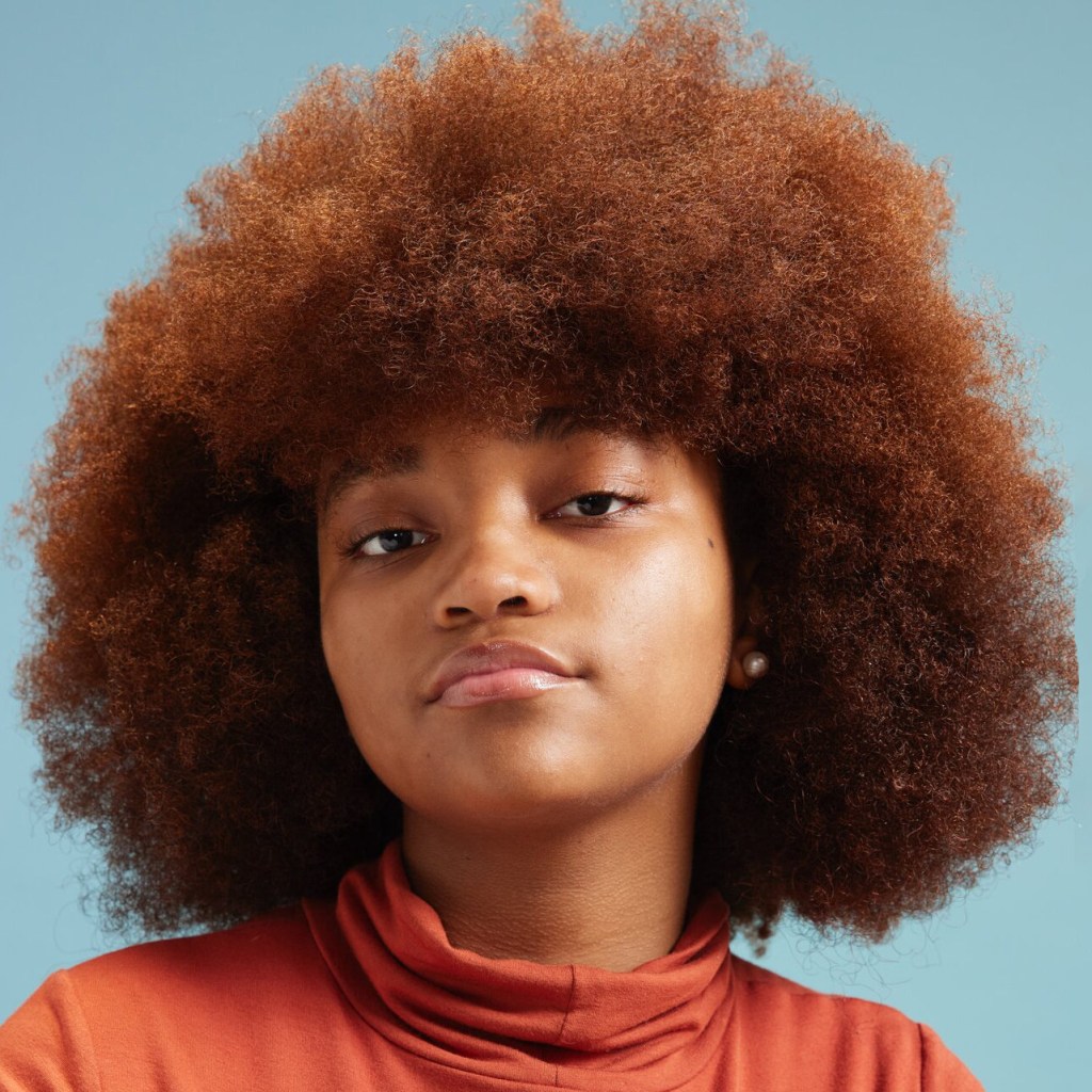 image of a Black girl in an orange top against a blue background